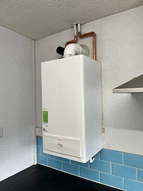 Boiler Supplier King's Lynn installing a wall-mounted Vaillant gas boiler with neat copper pipework in a modern kitchen.