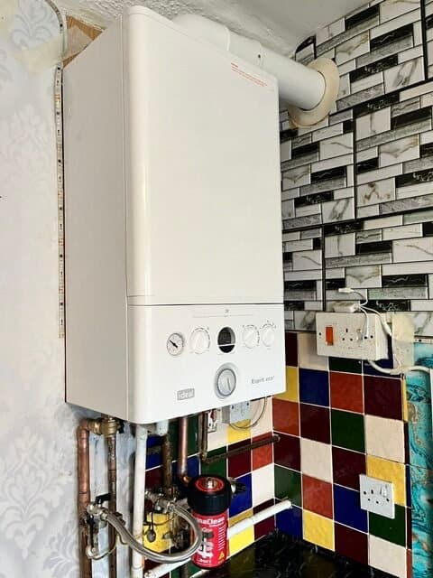 Gas Engineer King's Lynn installing a modern wall-mounted combi boiler with neatly fitted copper pipework and magnetic filter in a UK home.