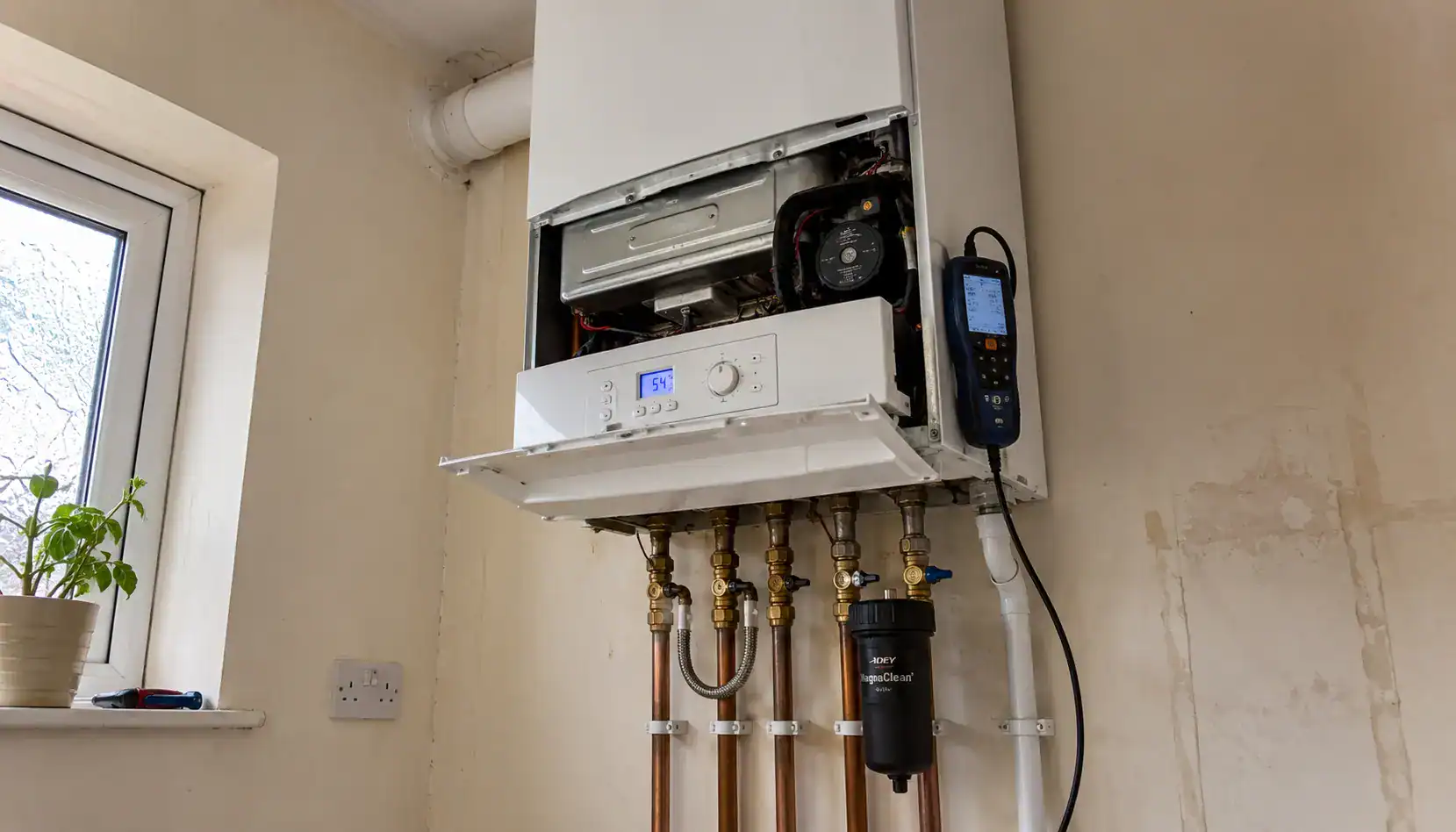 Gas boiler servicing in King's Lynn showing a wall-mounted boiler undergoing a professional annual service with flue gas analyser connected and internal components exposed.