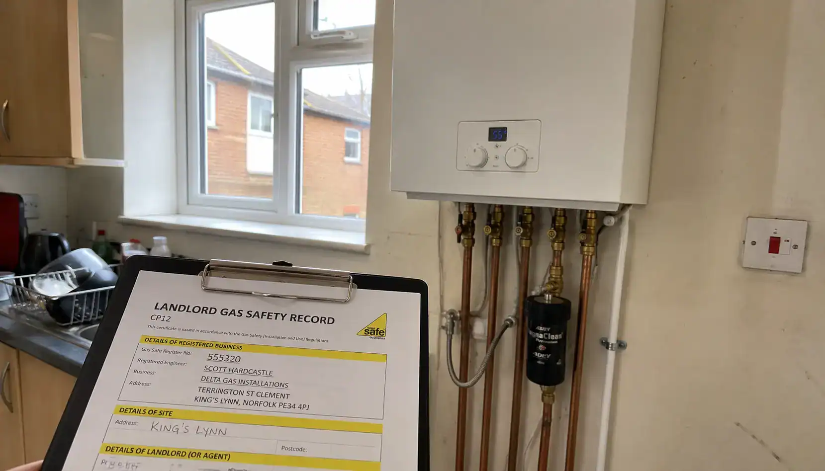 Gas Safe registered landlord gas safety inspection in progress on a wall-mounted combi boiler at a rental property in King's Lynn with CP12 certificate clipboard and flue gas analyser.